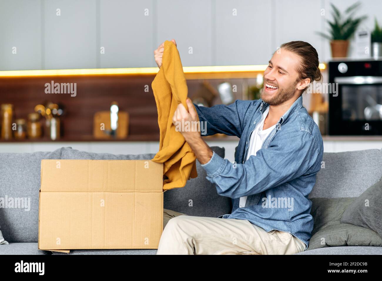 A satisfied smiling guy unpacks his long awaited package, examines the ...