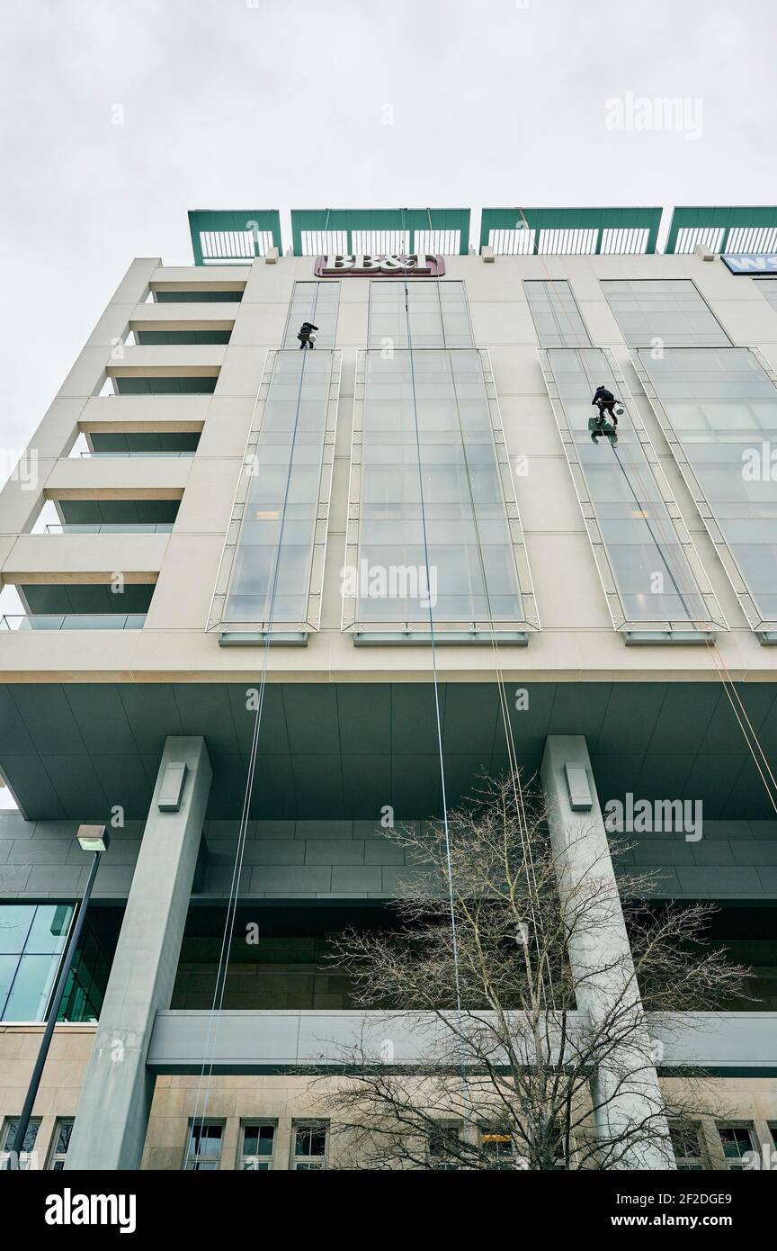 Window washer cleaning the outside windows of a high rise building from a low angle, in Montgomery Alabama, USA. Stock Photo