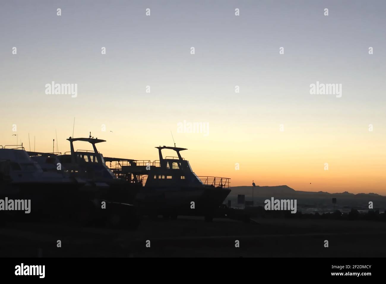 Boats silhouetted by the pier at sunrise in Gansbaai, South Africa Stock Photo