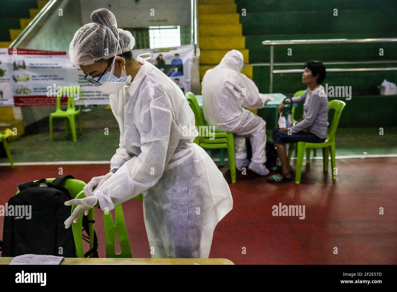 Health workers assist residents at a free COVID-19 swab test inside a gymnasium in Navotas city, Manila, Philippines. Stock Photo