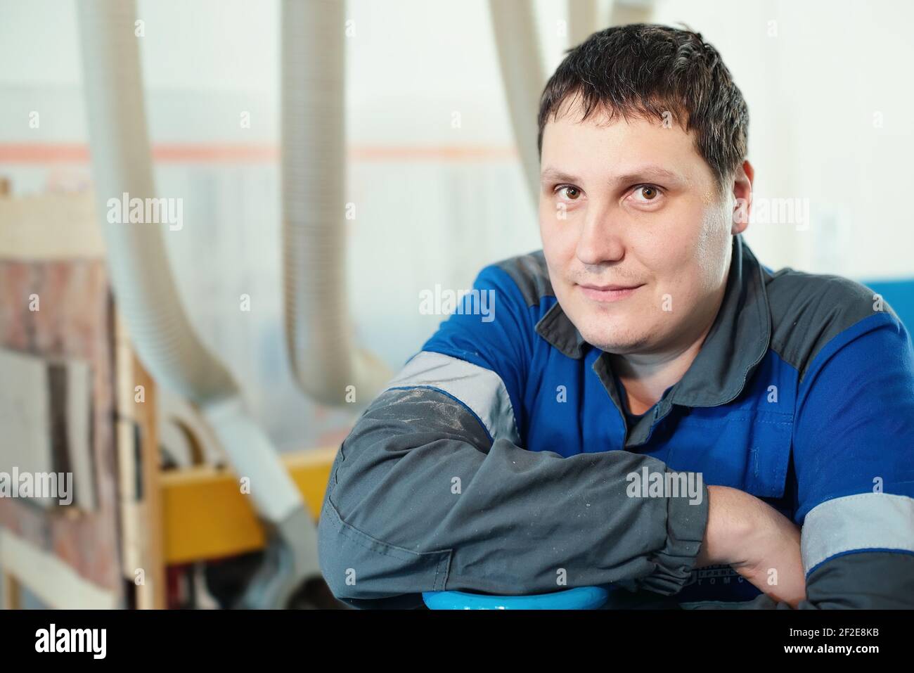 Portrait of a young worker in overalls at the workplace at the machine.  Stock Photo