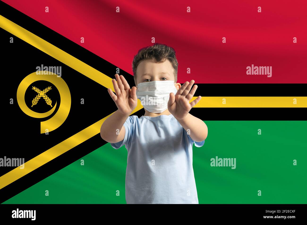 Little white boy in a protective mask on the background of the flag of Vanuatu. Makes a stop sign with his hands, stay at home Vanuatu. Stock Photo