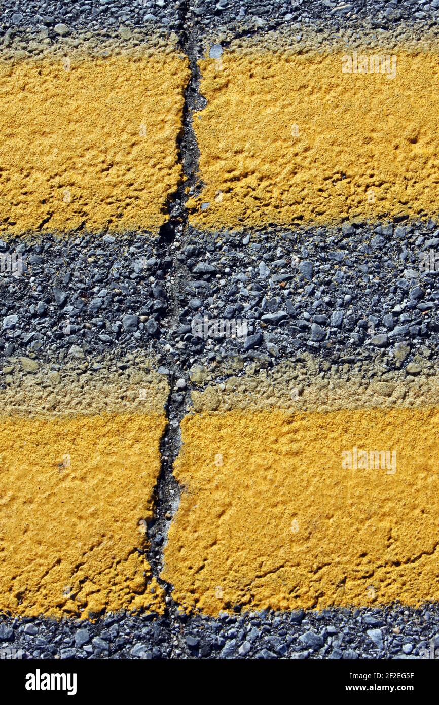 A double yellow road marking with a serious crack. Stock Photo