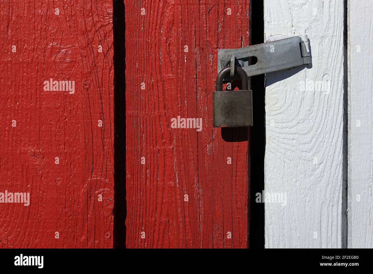 A padlock connecting red and white wooden panels. Stock Photo