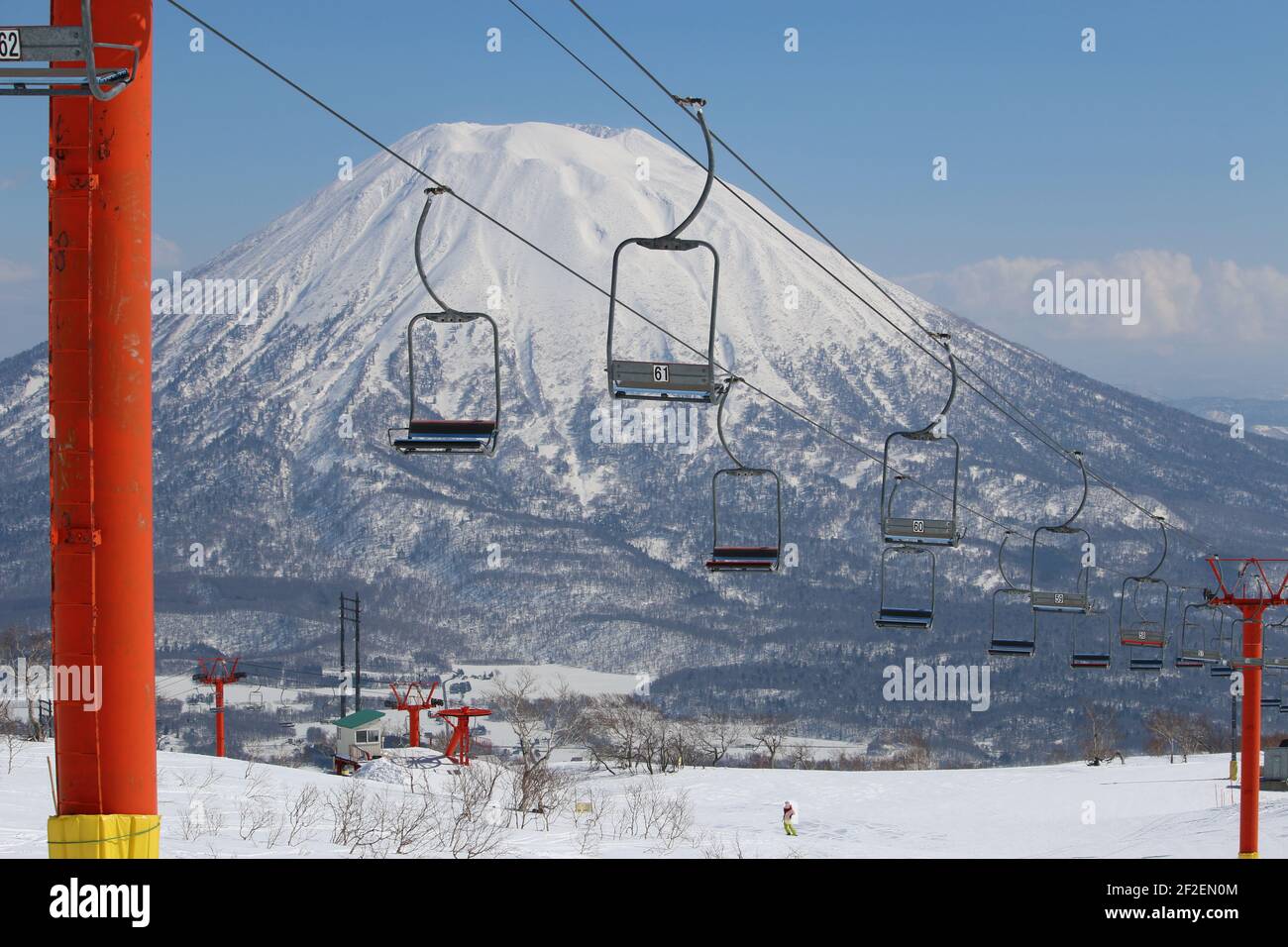Empty chair lifts at a ski resort with a snow-capped volcano in the background, Niseko, Hokkaido, Japan Stock Photo