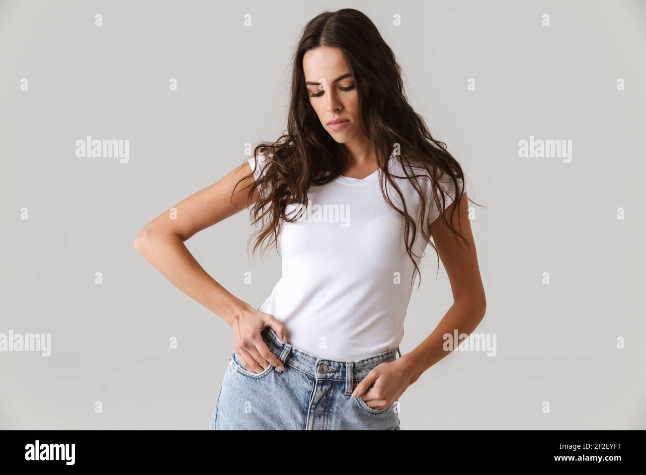 Brunette beautiful girl posing with hands in pockets isolated over ...