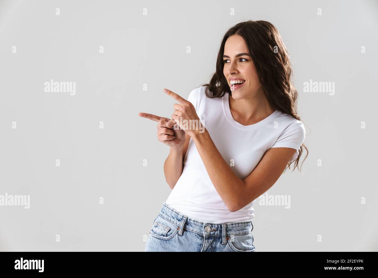 Happy beautiful girl smiling and pointing fingers aside isolated over ...