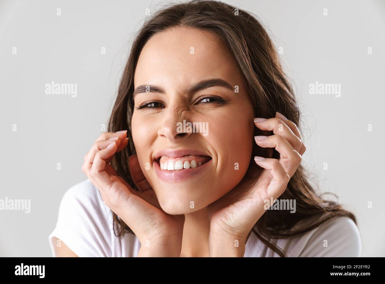 Joyful beautiful girl smiling and looking at camera isolated over white ...