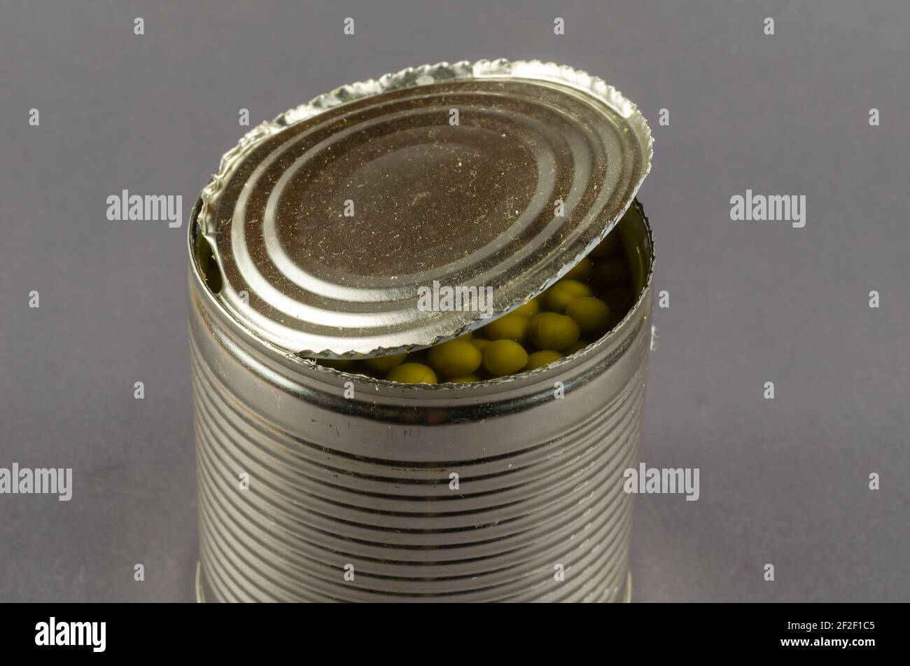 Open tin can on a gray background. Canned green peas. The can was