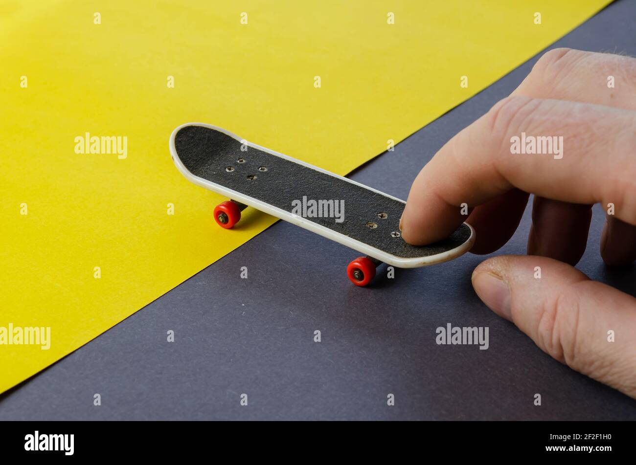 Hand and finger skateboard on gray-yellow background. A man's hand plays a mini  skateboard with red wheels on a two-tone background. Close-up, selecti  Stock Photo - Alamy
