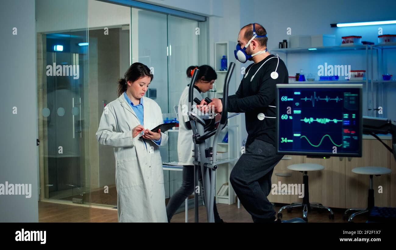 Sportsman with mask running on cross trainer in sports science