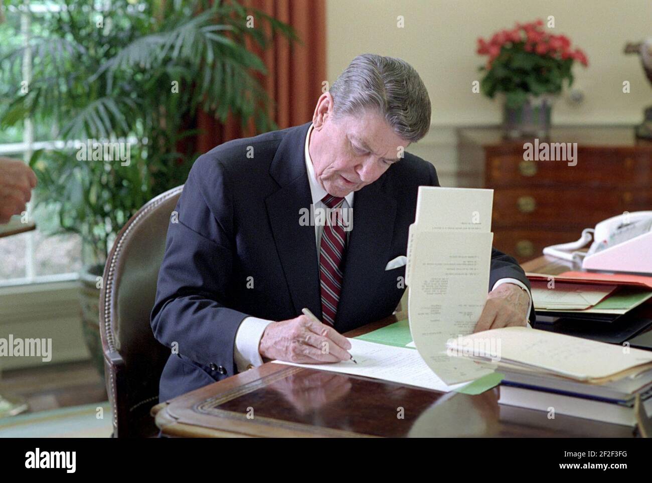 President Ronald Reagan signing veto of the Cranston resolution disapproving the Saudi Arabian arms in the Oval Office. Stock Photo