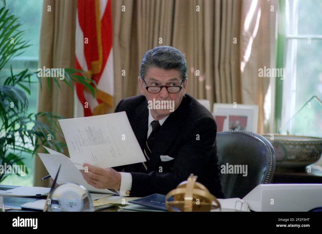 President Ronald Reagan wearing glasses while working at his desk in