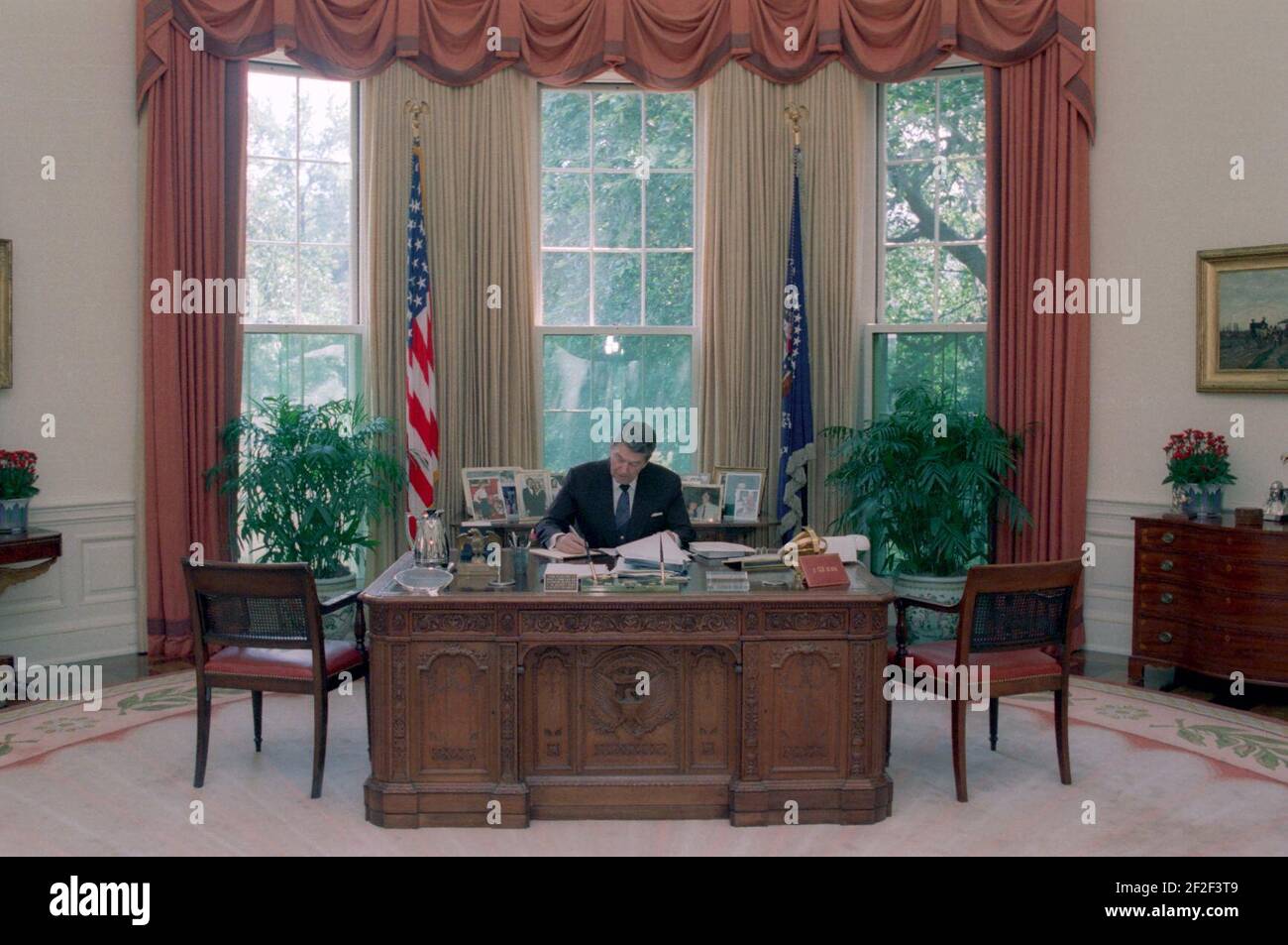 President Ronald Reagan working at his desk in the Oval Office. Stock Photo