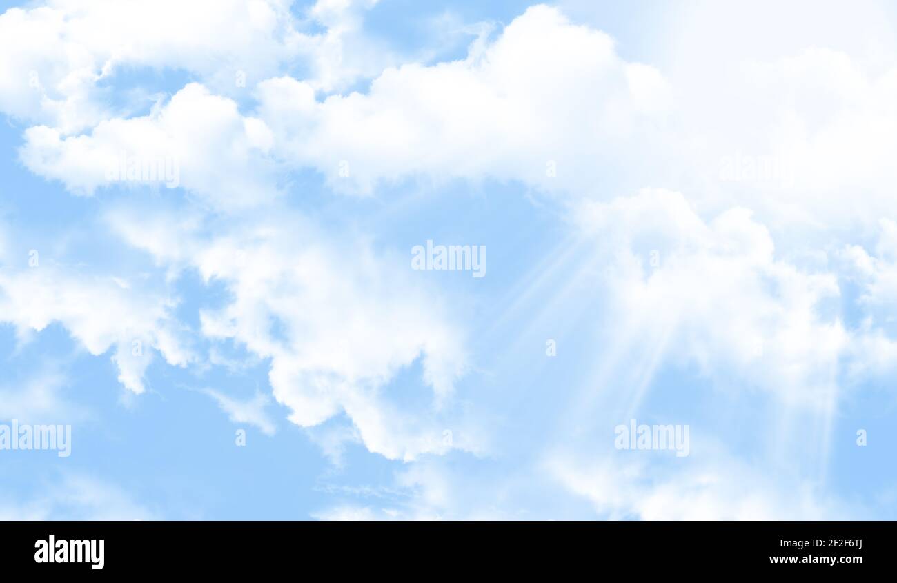 Blue sky background with fluffy white clouds and sun beams. Spring or ...