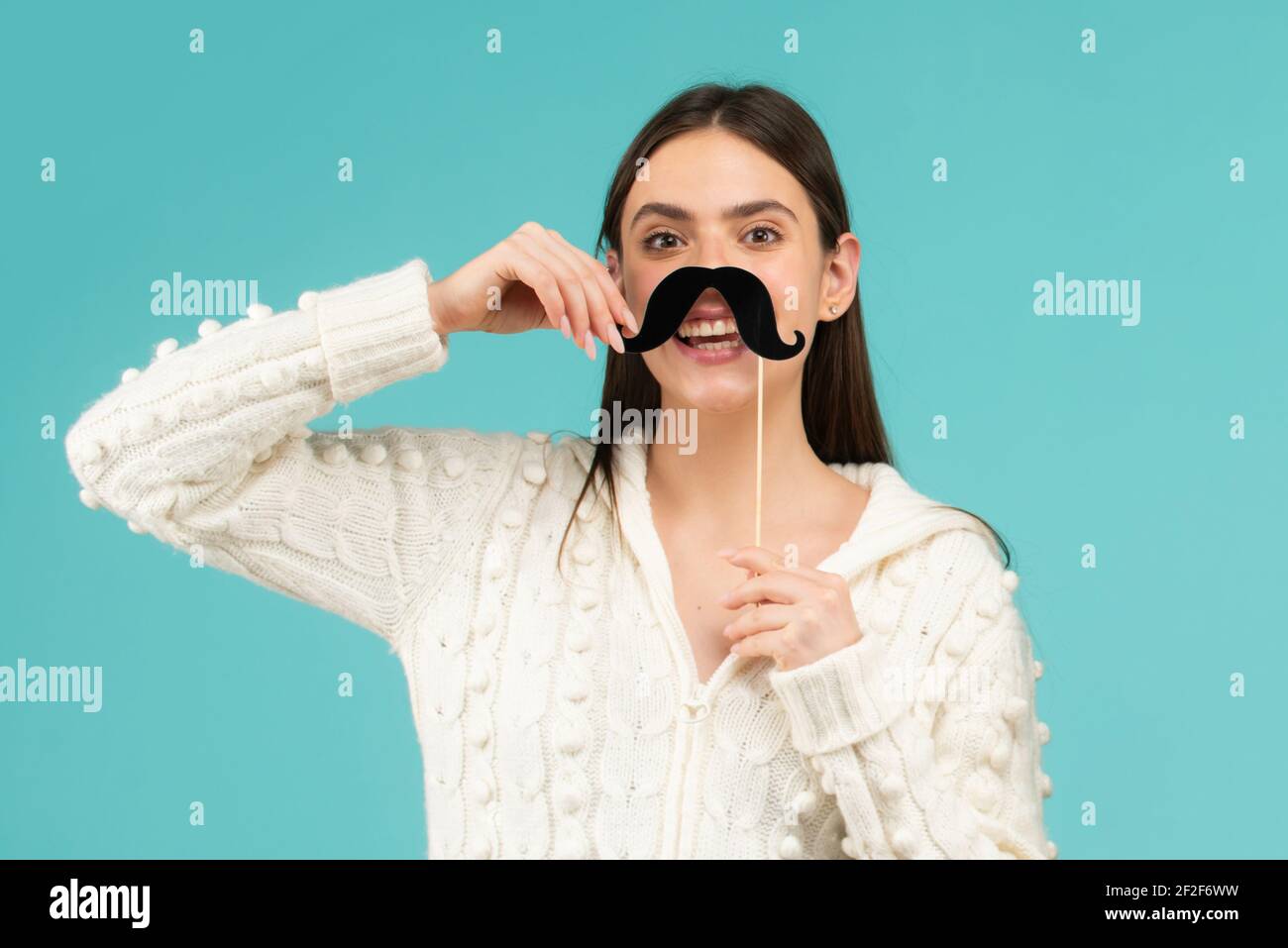 Photo booth party. Fake mustache on stick. Happy woman holding mustache and smiling. Stock Photo