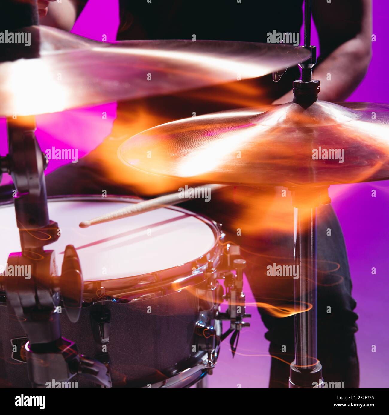 Closeup male hands playing the drums isolated on bluepink background