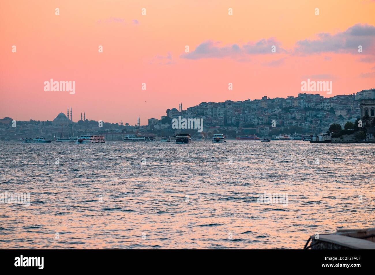 A beautiful calm sea during a golden sunset with boats and a stunning Istanbul city in the background, Turkey Stock Photo