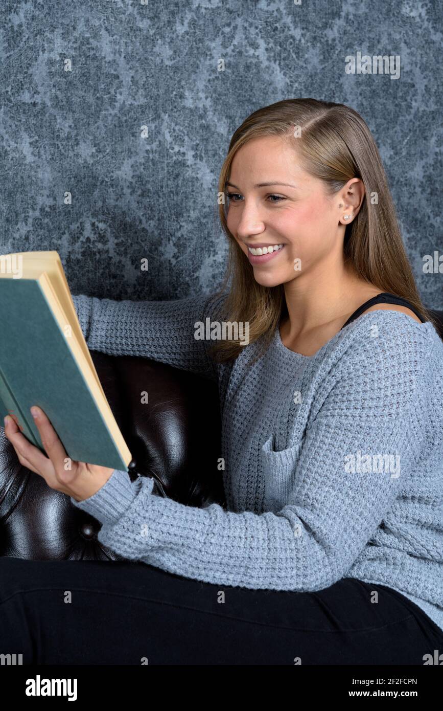 Student sits in reading corner and smiles at her book Stock Photo