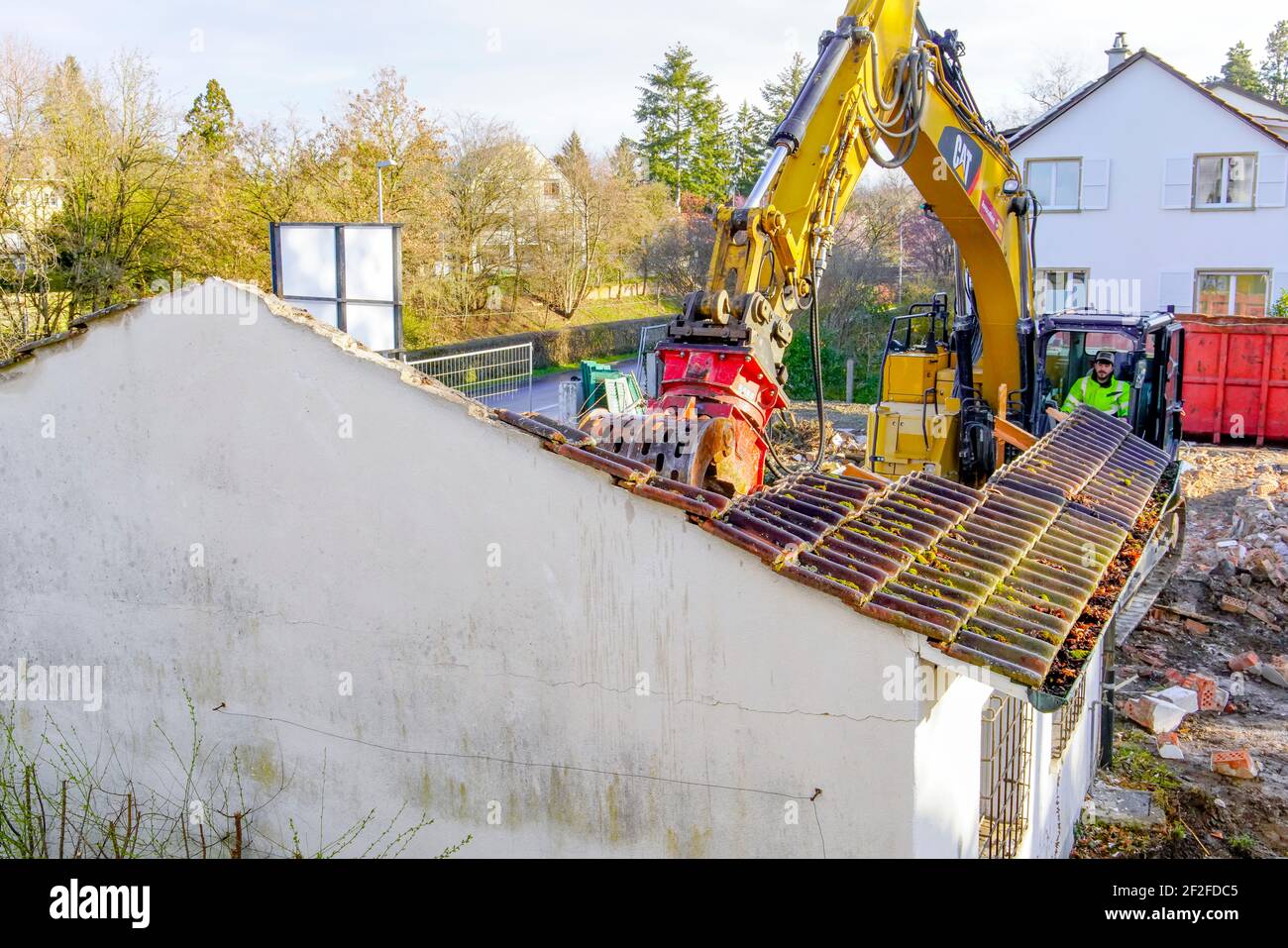 Heavy bulldozer tearing down a villa and frees up space for a new building. Riehen, Switzerland. Stock Photo