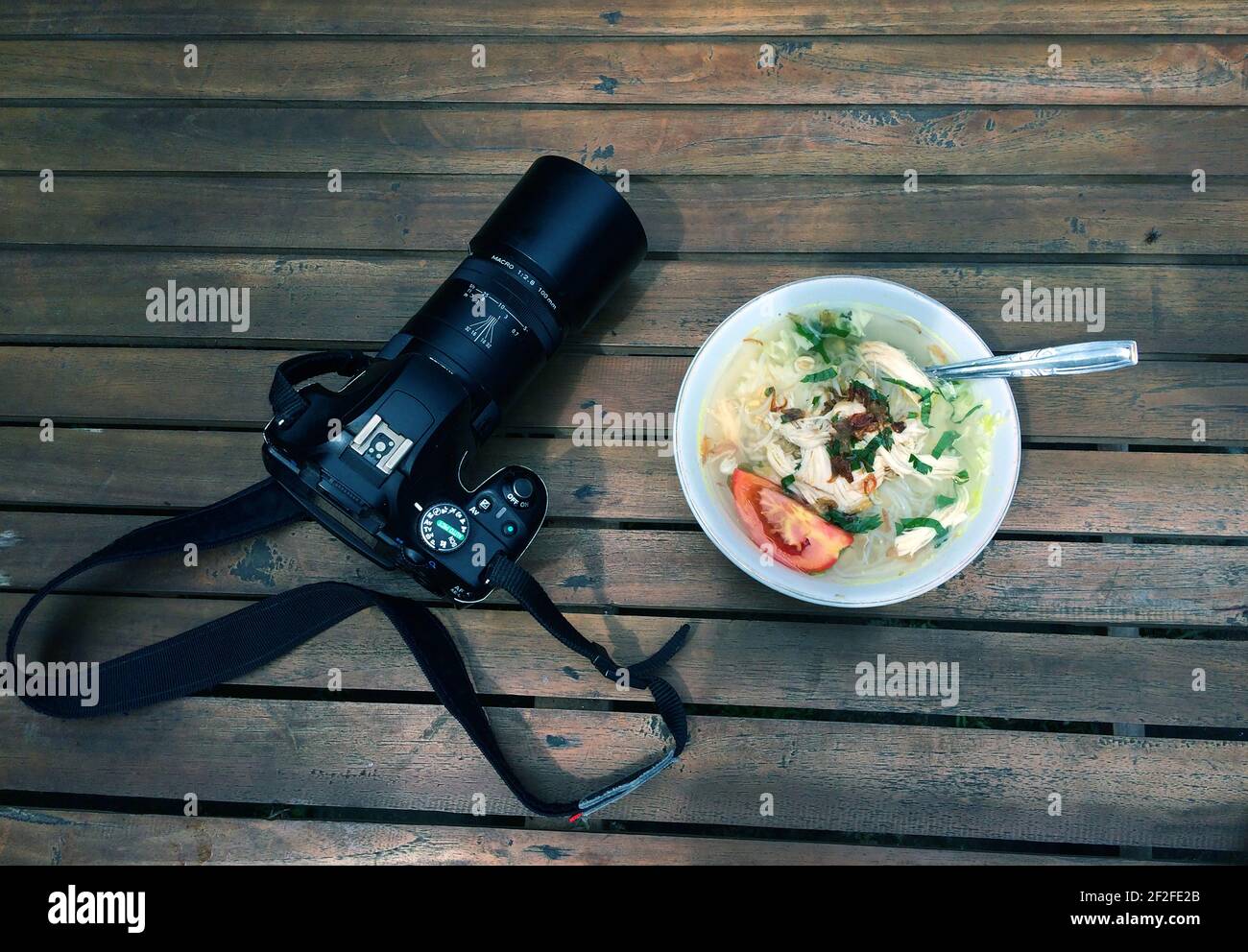 Soto Ayam, Indonesian traditional chicken soup and a camera on the wooden table Stock Photo