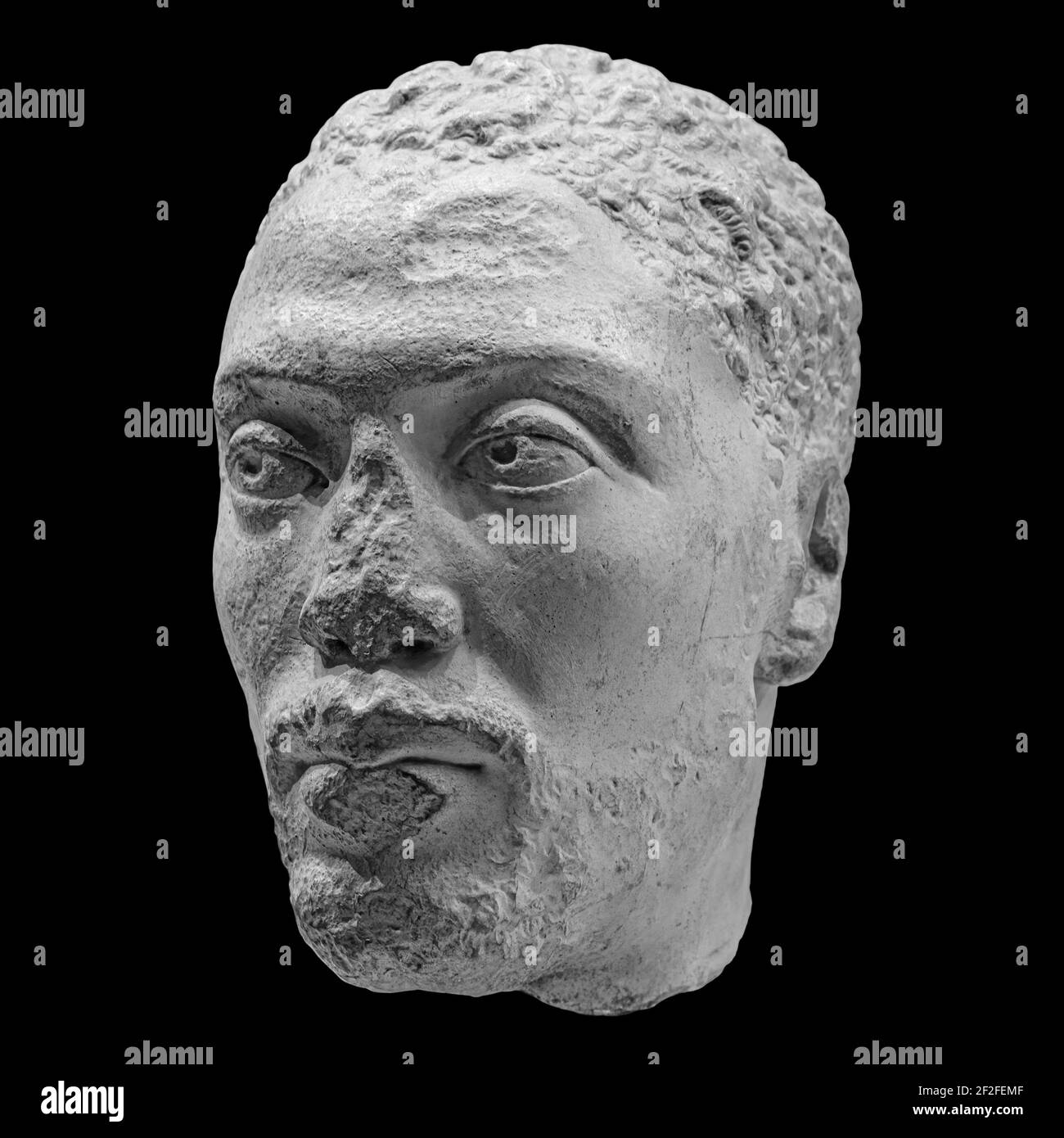 Antique head of the ancient man priest of Ancient Egyptian Isis with cracks sculpture. Face statue isolated on black background Stock Photo