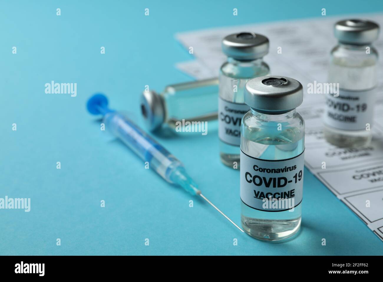Concept of Covid - 19 vaccination with vials and syringe on blue ...
