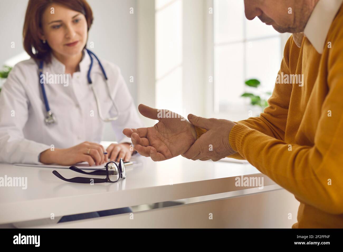Patient suffering from wrist pain complaints on ache symptom to doctor Stock Photo