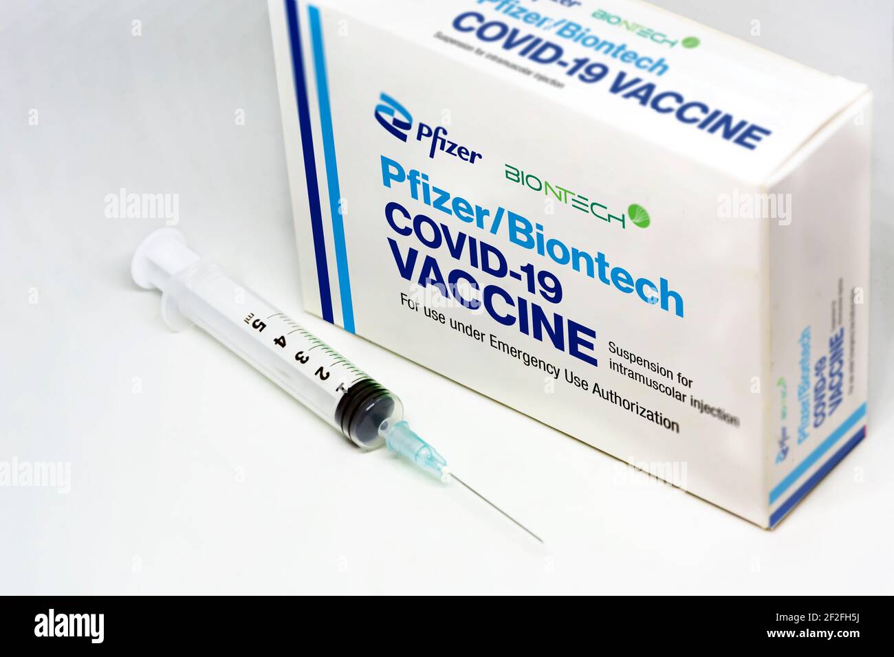 New York USA, february 5th 2021: A syringe next to the Pfizer BioNTech Covid-19 vaccine box isolated on a white background. Health and prevention. Stock Photo
