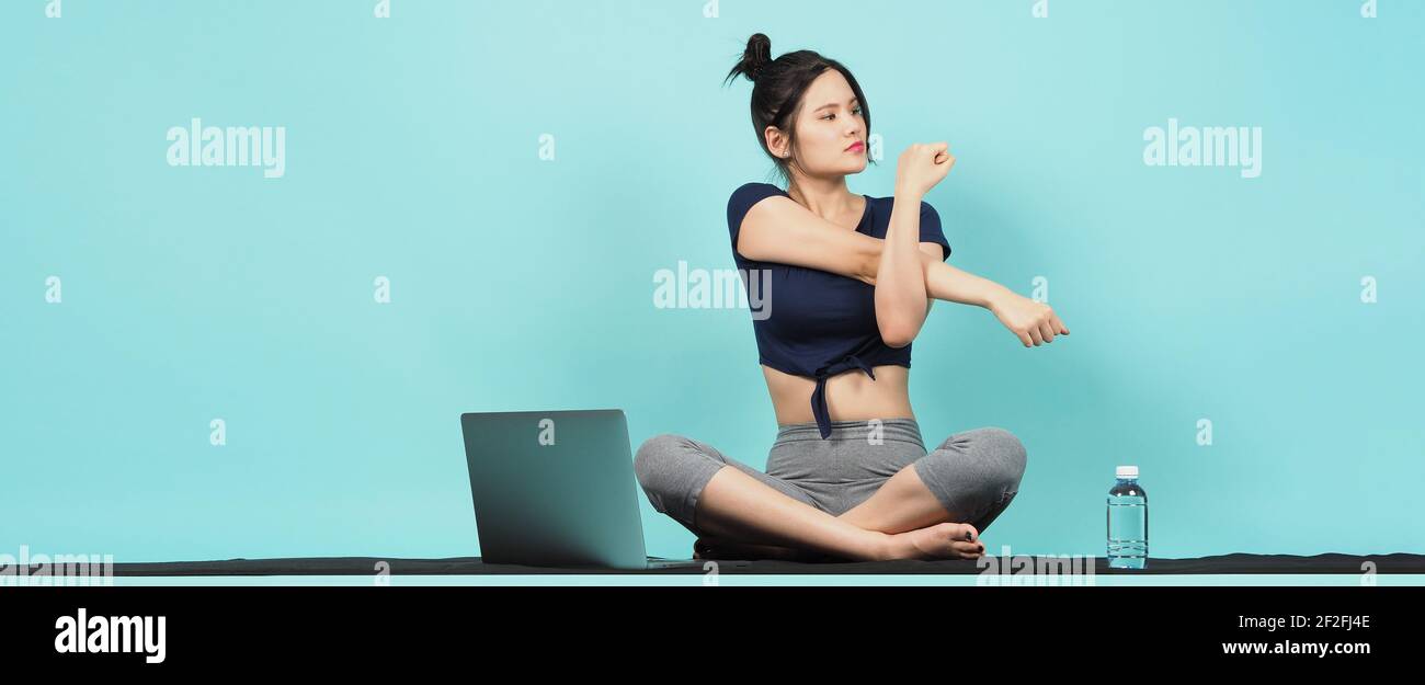 Fitness influencer. Sporty woman Blogger. workout training online via laptop. blue green background. Training woman KOL in sportswear shoots video exe Stock Photo