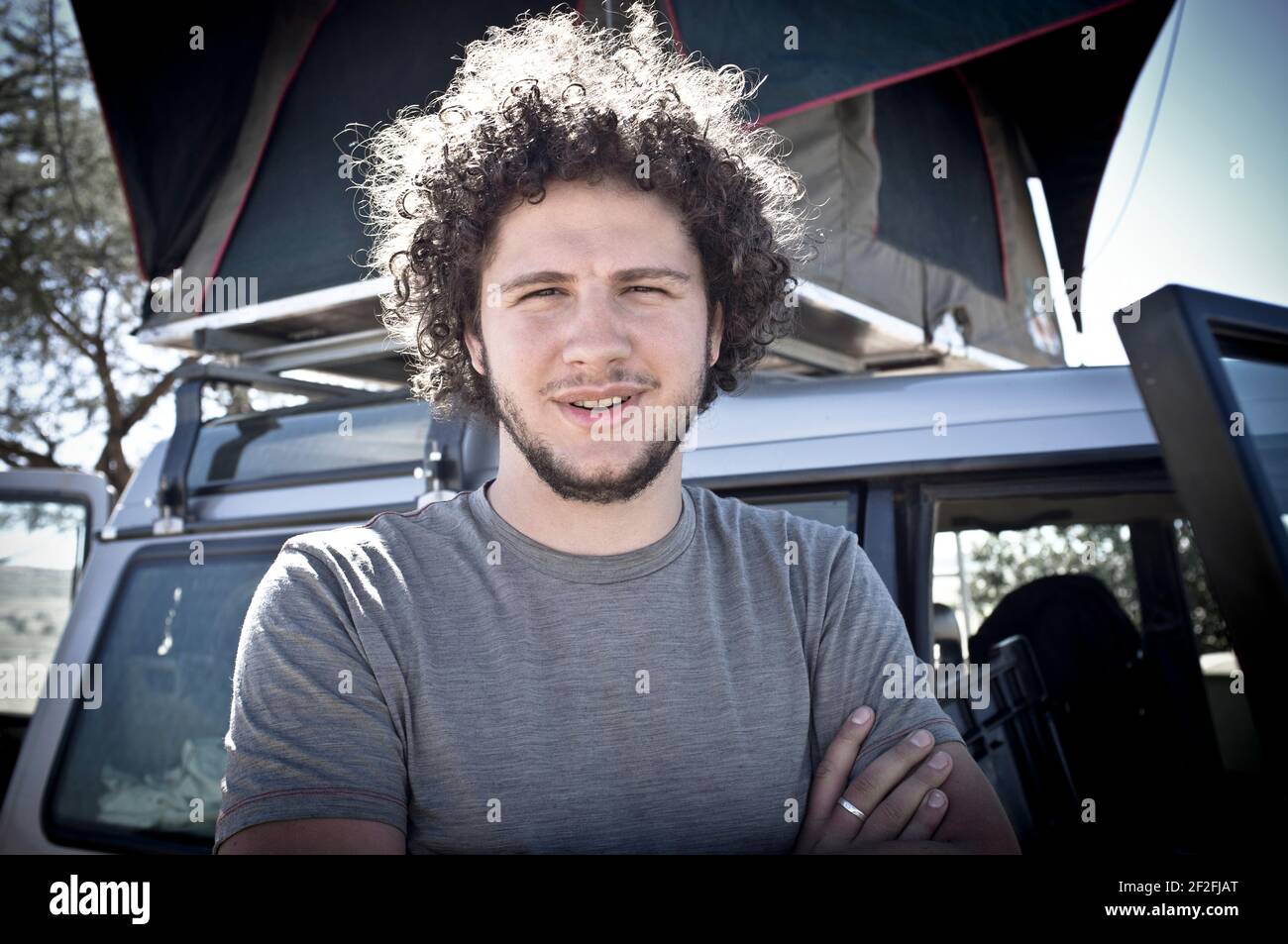 Young man stands in front of vehicle, half portrait Stock Photo