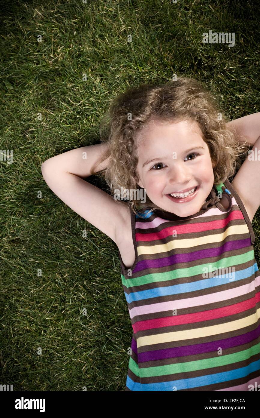 Young girl is lying on the meadow with her arms crossed, half portrait
