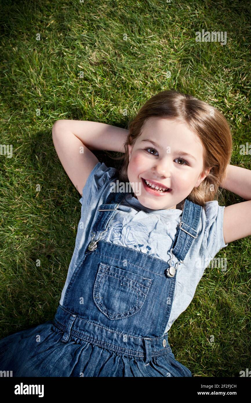 Young girl is lying on the meadow with her arms crossed, half portrait Stock Photo