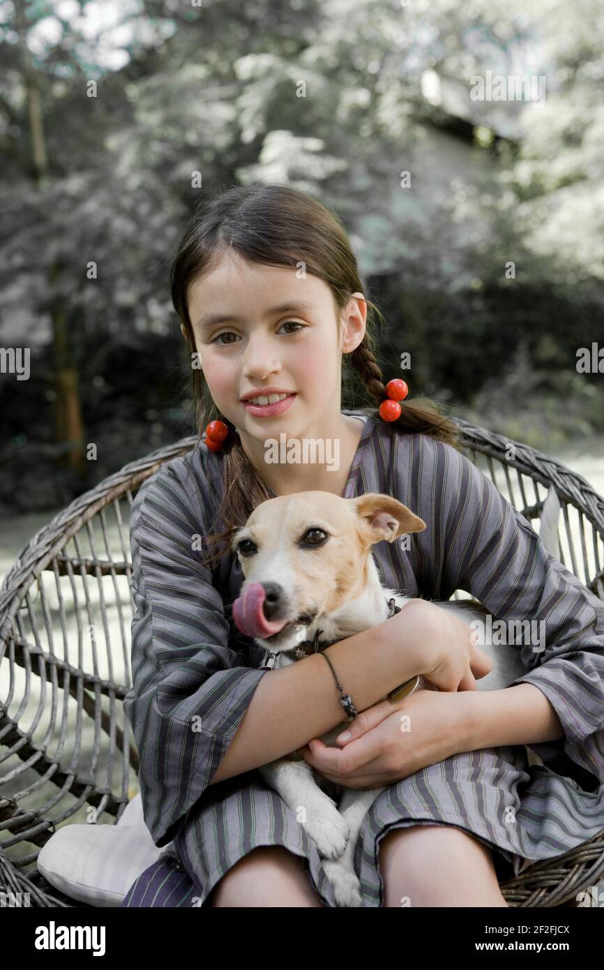 Girl sits on garden chair with dog on lap Stock Photo