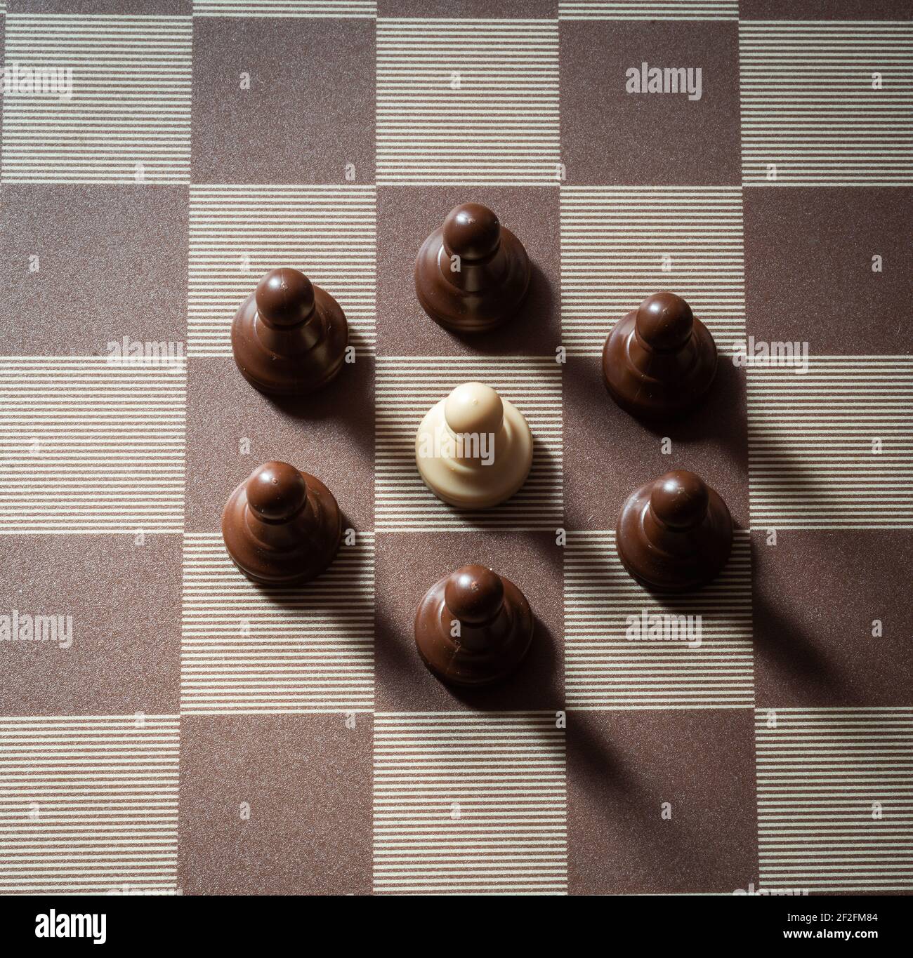 pawn on chess board surrounded by adversary concept of adversity ,discimination ,equality . Stock Photo