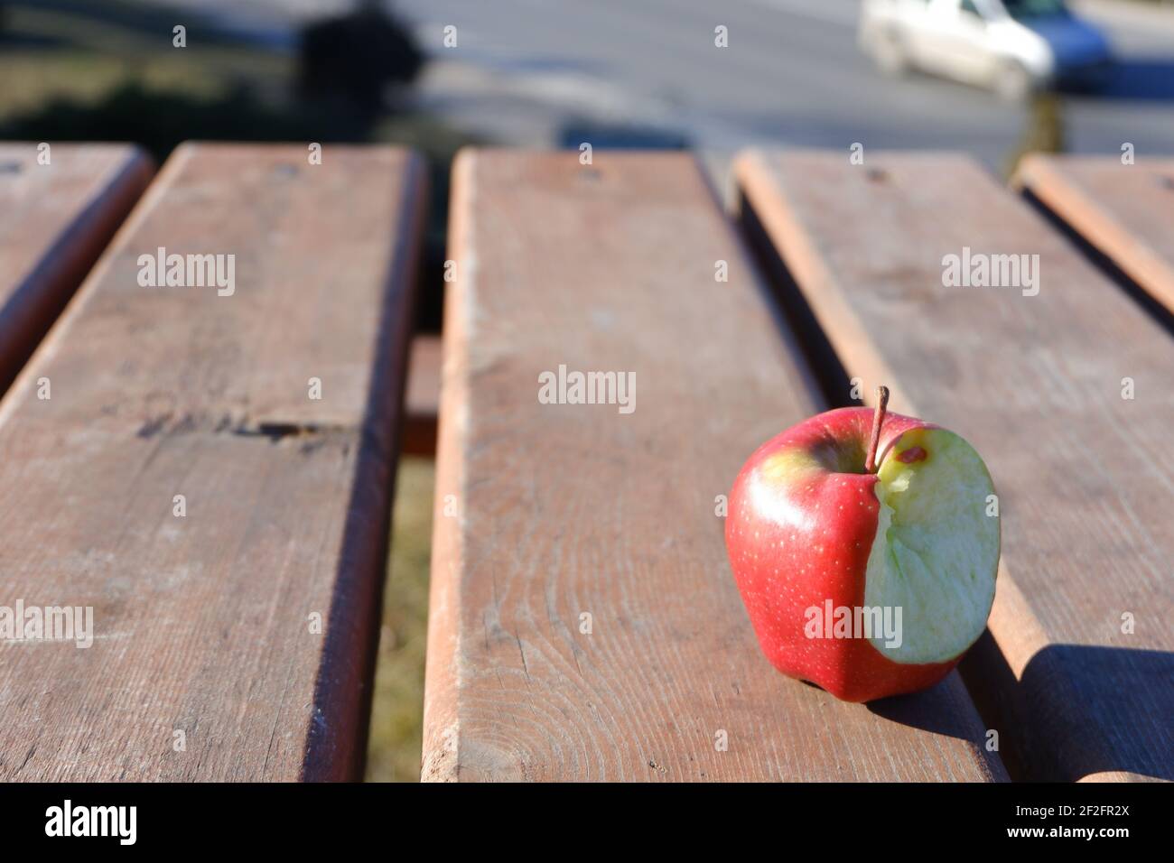 Bitten Red apple on wooden table outdoor Stock Photo