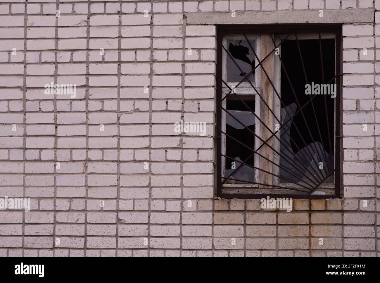 Broken glass in a window with a metal grate. Stock Photo