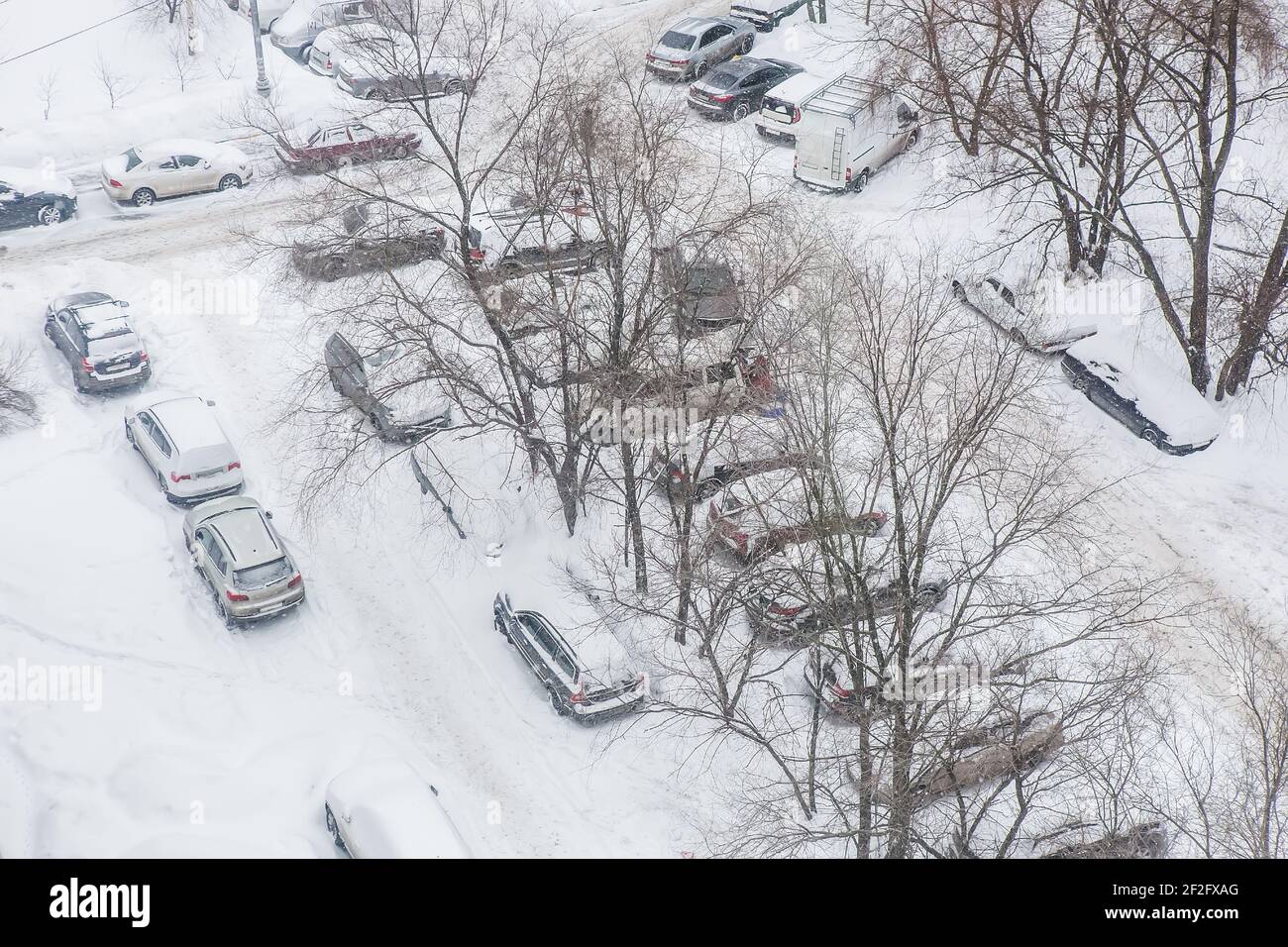 Snow-covered cars parked in the courtyard of a residential area in ...