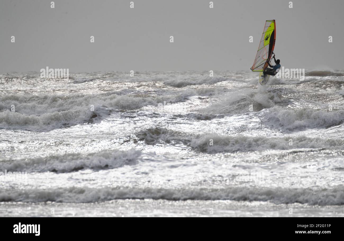 A windsurfer surfs in the rough sea off of West Wittering beach in West Sussex. Picture date: Friday March 12, 2021. Stock Photo