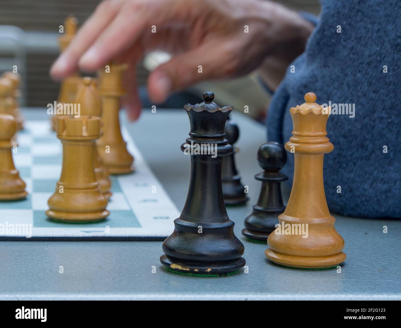 Man's hand on chess piece with other chess playing pieces sitting off the board on a table. Close up. Stock Photo