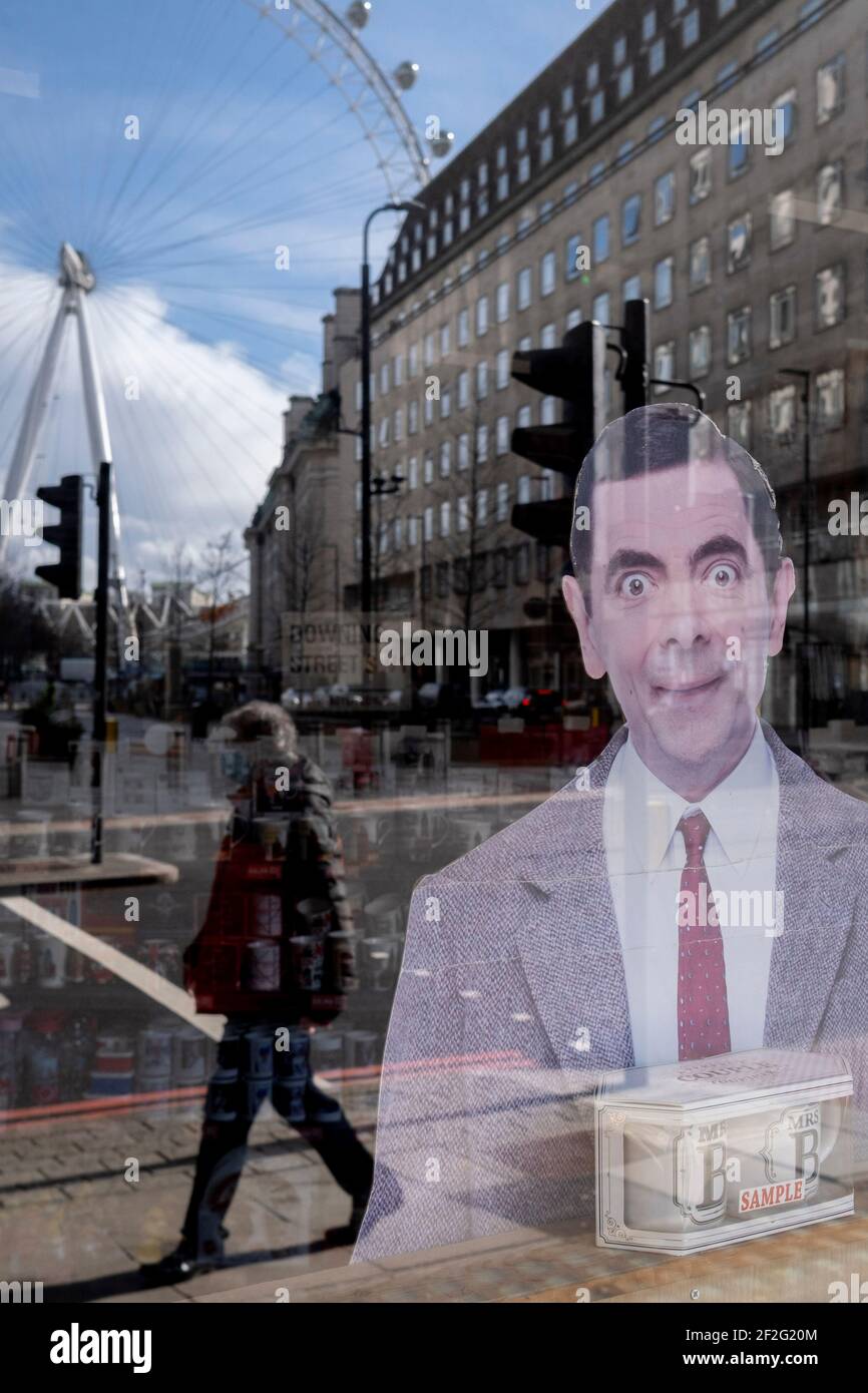 The character known as Mr Bean, one of the UK's successful TV comedy exports, looks out from a tourist trinket retailer's window in Waterloo, where the London Eye still revolves while empty during the third lockdown of the Coronavirus pandemic, on 11th March 2021, in London, England. Stock Photo