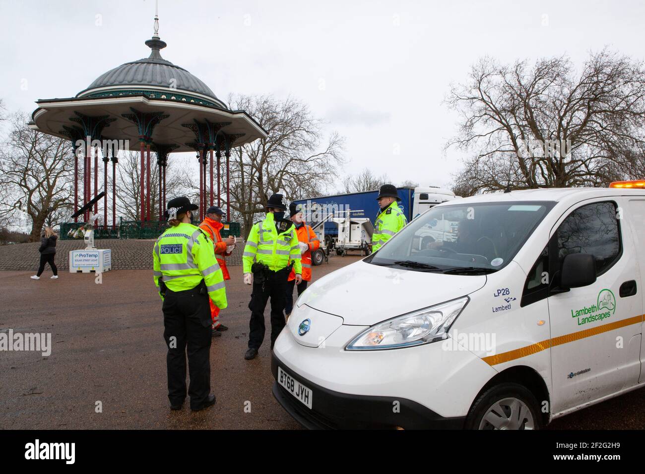 London, UK. 12th Mar, 2021. Lambeth Council workers set up lighting at Clapham Common bandstand for the disputed Reclaim These Streets vigil tomorrow. Metropolitan Police officers came to discuss what was happening and phoned in a report to their bosses. Reclaim the Streets are in court today fighting for the right for the vigil to go ahead despite lockdown restrictions. Credit: Anna Watson/Alamy Live News Stock Photo