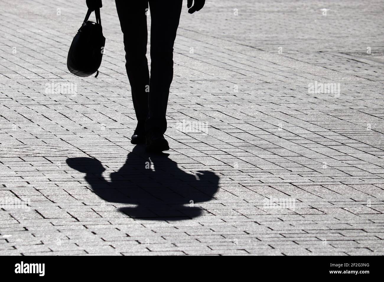 Black silhouette of slim man with briefcase walking on the street ...