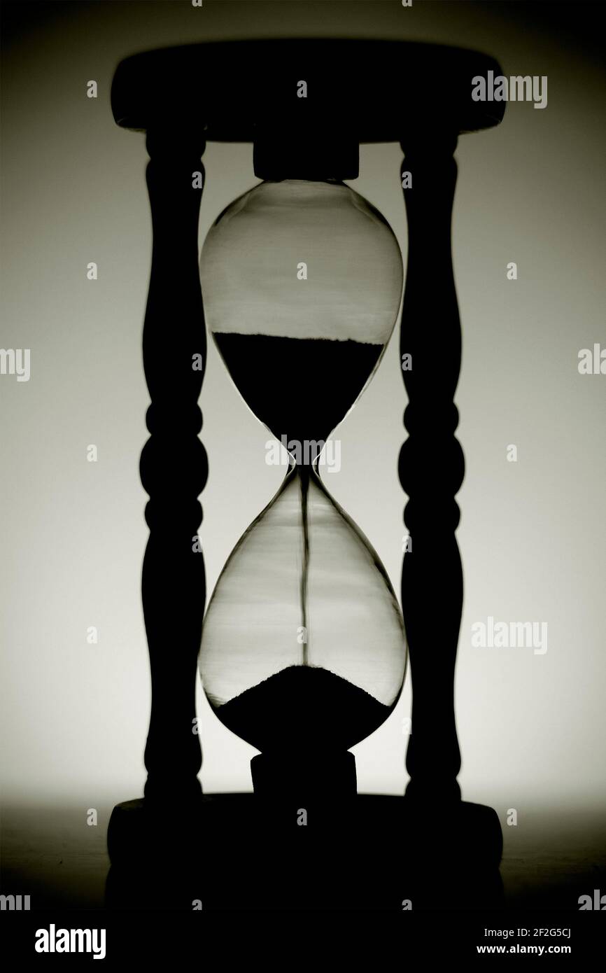 Backlit hourglass in black and white in a low key. Black and white image of a sand clock. Stock Photo