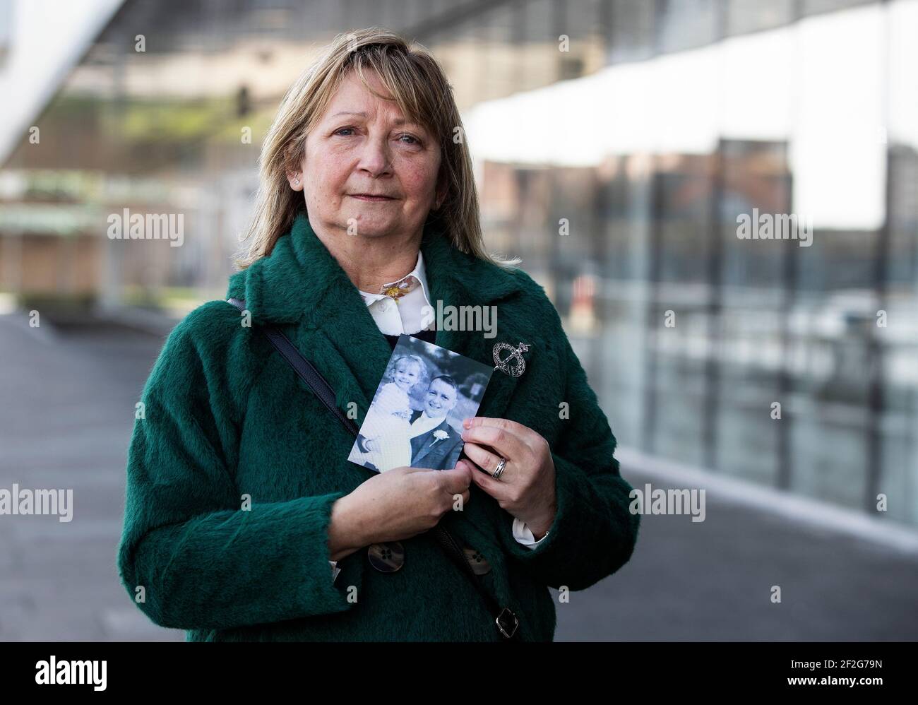 Ella McMahon holds a photograph of her son Gerard McMahon holding his niece Abbie McMahon, outside the International Convention Centre, after a coroner delivered inquest findings surrounding the death of Gerard McMahon after he was restrained by police. A coroner has criticised aspects of a police restraint operation involving the DJ who later died after suffering a cardiac arrest but said the force used by officers was not excessive. Gerard McMahon, from the Short Strand area of Belfast, died in hospital on September 8, 2016.Picture date: Friday March 12, 2021. Stock Photo