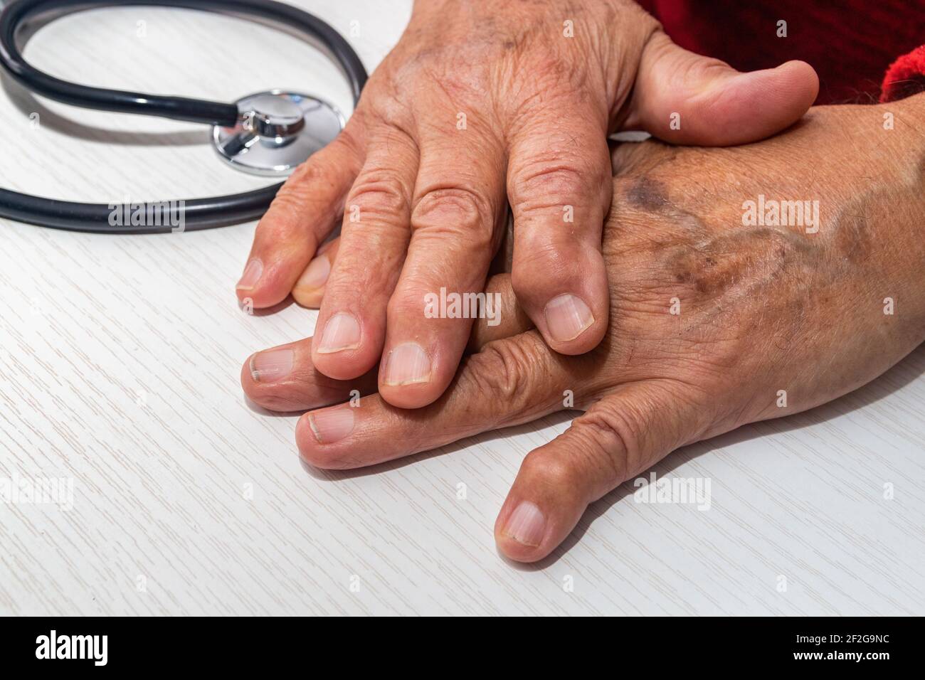 Hand of elderly man with osteoarthritis at doctor's office on white table Stock Photo