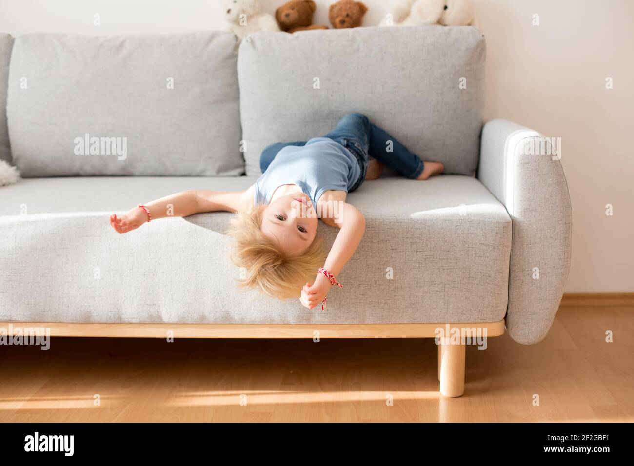Toddler child, hanging upside down from a couch at home, smiling