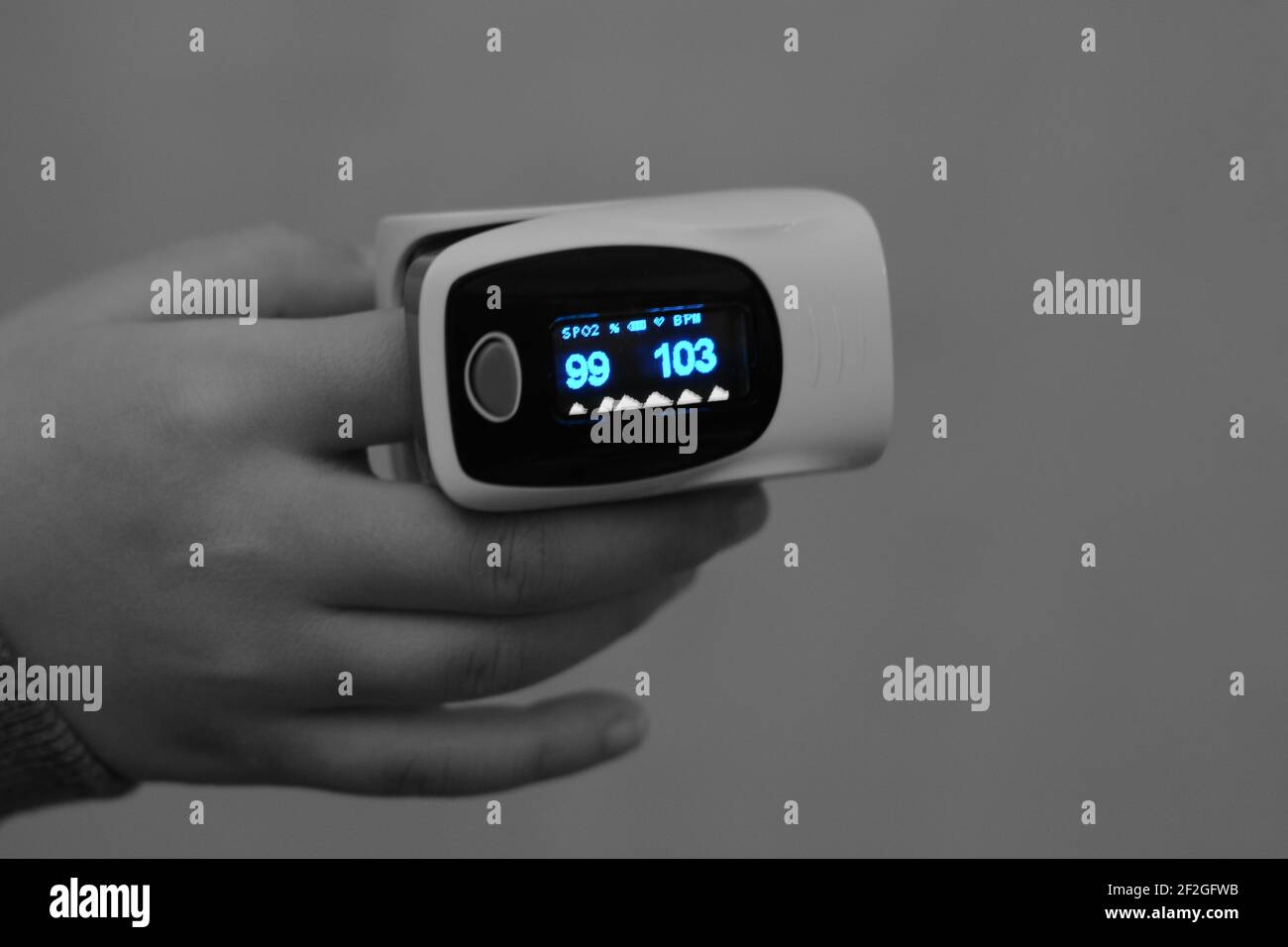 fingertip pulse oximeter equipment connected to the index finger of a child measuring oxygen saturation in blood and heart rate Stock Photo