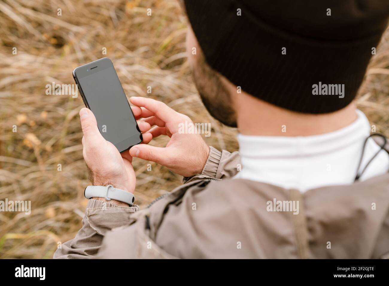 Young sportsman in hat using mobile phone while working out in nature Stock Photo