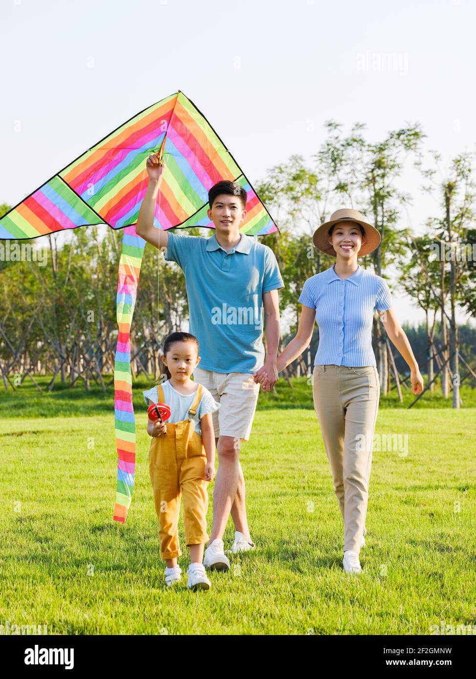 Happy family of three flying kites in the park smiling Stock Photo - Alamy